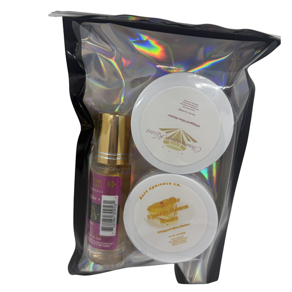 A black zip lock style pack featuring two sample sized shea butters in the scents pineapple upside down cake and champagne kisses. Accompanied by a Prada Candy inspired roller